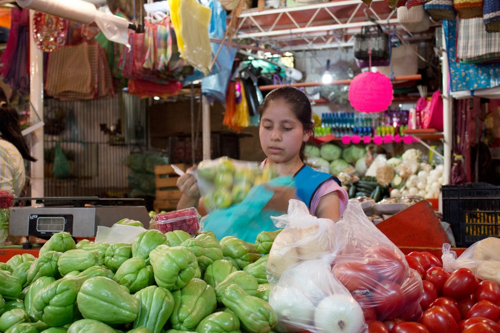 Alejandra pone fruto para un cliente en su puesto en el mercado al aire libre de Tenancingo. Abandonó sus estudios para mantener a su familia a través de su ingreso en el mercado, pero ella sueña con ser médico algún día.